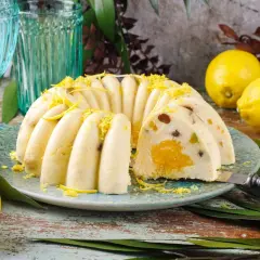 Pyszna babka z owocami, udekorowana skórką cytrynową, prezentuje się apetycznie na talerzu. Obok leżą świeże cytryny.