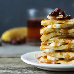 Stos placków bananowych polanych karmelem, ozdobiony orzechami. Idealne na śniadanie.