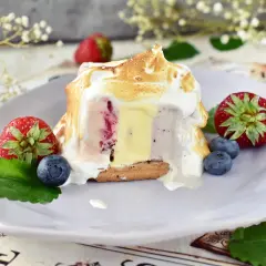 Pyszne baked alaska z lodami, owocami i bezą na talerzu.
