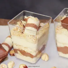 Pyszne deserki Kinder Bueno w pucharkach, warstwowo ułożone z kremem i czekoladą, posypane orzechami.