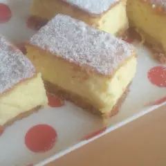 Kawałki puszystego ciasta, posypane cukrem pudrem, wyglądają jak sernik bez sera. Idealne na deser.