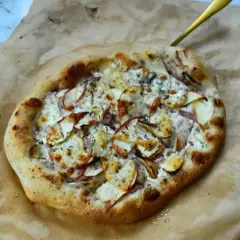 Apetyczna pizza bianca z jabłkami i serem, podana na papierze do pieczenia.