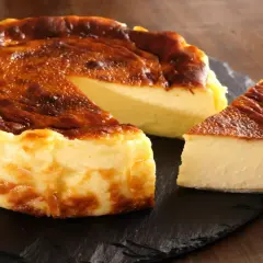 Pyszny, lekko przypieczony sernik wiedeński z kremowym wnętrzem, podany na czarnej desce.
