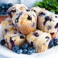 Stos pysznych muffinek z borówkami, polanych lukrem, ozdobionych świeżymi borówkami.