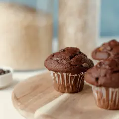 Pyszne muffinki czekoladowe, gotowe do jedzenia. W tle słoiki z cukrem i mąką.