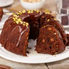 Pyszna babka czekoladowa z polewą i pistacjami, kawałek ciasta z orzechami i bakaliami.