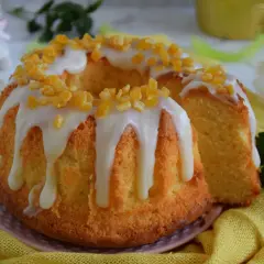 Puszysta babka majonezowa z lukrem i kandyzowaną skórką pomarańczową, ozdobiona wiosennymi kwiatami.