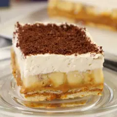 Pyszna tarta banoffee z warstwami banana, karmelu i bitej śmietany, posypana czekoladową posypką.