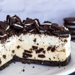 Pyszny sernik oreo z kawałkami ciastek i kremową masą, posypany pokruszonymi oreo.