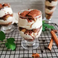 Pyszne tiramisu w pucharkach, warstwowo ułożone z kremem i biszkoptami, posypane kakao. Idealne na deser.