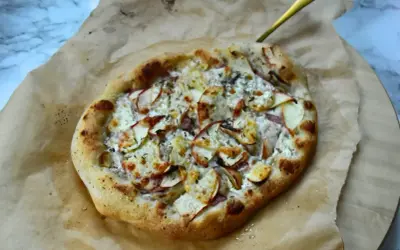 Apetyczna pizza bianca z jabłkami i serem, podana na papierze do pieczenia.