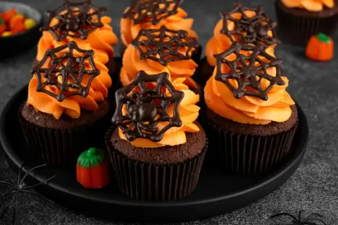 Przerażająco pyszne babeczki halloween z pomarańczowym kremem i czekoladowymi pajęczynkami. Idealne na straszne przyjęcie!