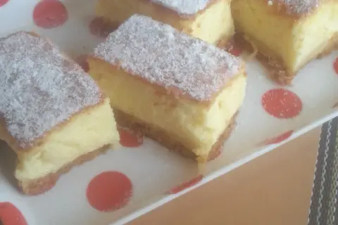 Kawałki puszystego ciasta, posypane cukrem pudrem, wyglądają jak sernik bez sera. Idealne na deser.