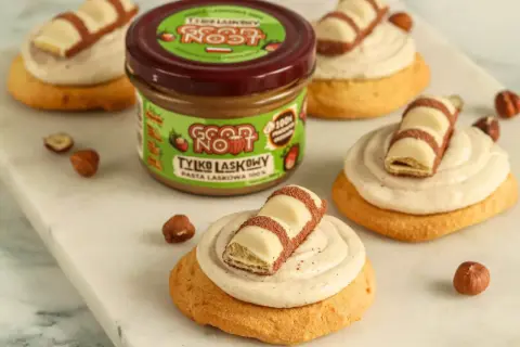 Pyszne ciasteczka inspirowane przepisem na crumbl cookies, z kremem i kawałkami Kinder Bueno. Słoik pasty z orzechów laskowych Good Now zachęca do eksperymentów.