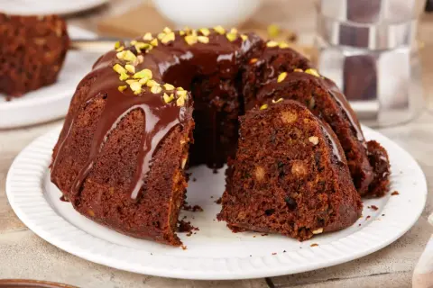 Pyszna babka czekoladowa z polewą i pistacjami, kawałek ciasta z orzechami i bakaliami.