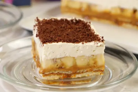 Pyszna tarta banoffee z warstwami banana, karmelu i bitej śmietany, posypana czekoladową posypką.