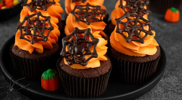 Przerażająco pyszne babeczki halloween z pomarańczowym kremem i czekoladowymi pajęczynkami. Idealne na straszne przyjęcie!