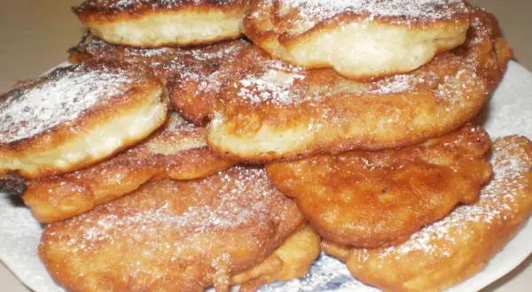 Góra puszystych racuchów bez drożdży, posypanych cukrem pudrem. Idealne na szybkie śniadanie lub deser.