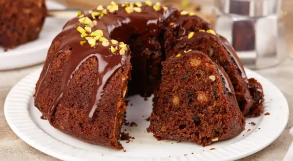 Pyszna babka czekoladowa z polewą i pistacjami, kawałek ciasta z orzechami i bakaliami.