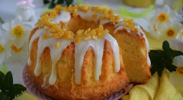 Puszysta babka majonezowa z lukrem i kandyzowaną skórką pomarańczową, ozdobiona wiosennymi kwiatami.
