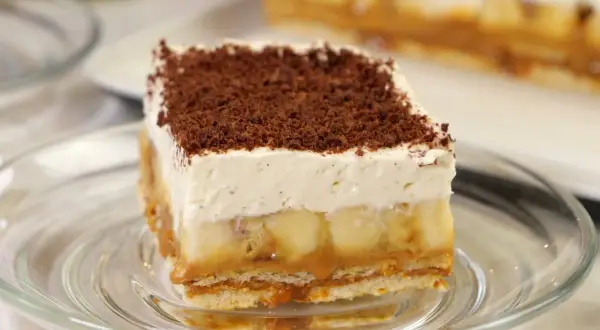 Pyszna tarta banoffee z warstwami banana, karmelu i bitej śmietany, posypana czekoladową posypką.
