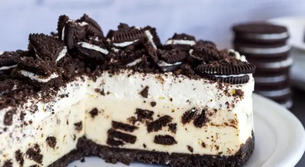 Pyszny sernik oreo z kawałkami ciastek i kremową masą, posypany pokruszonymi oreo.