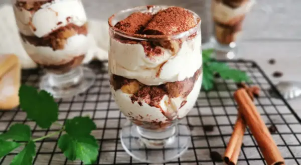 Pyszne tiramisu w pucharkach, warstwowo ułożone z kremem i biszkoptami, posypane kakao. Idealne na deser.