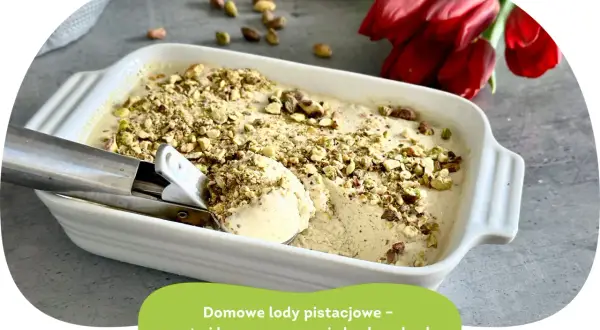 Kremowe lody pistacjowe w białej misce, posypane orzechami. Obok czerwone tulipany.