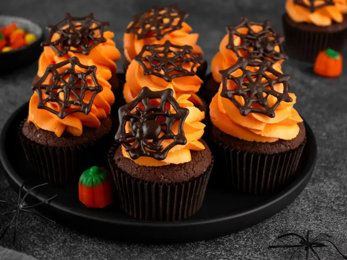 Przerażająco pyszne babeczki halloween z pomarańczowym kremem i czekoladowymi pajęczynkami. Idealne na straszne przyjęcie!