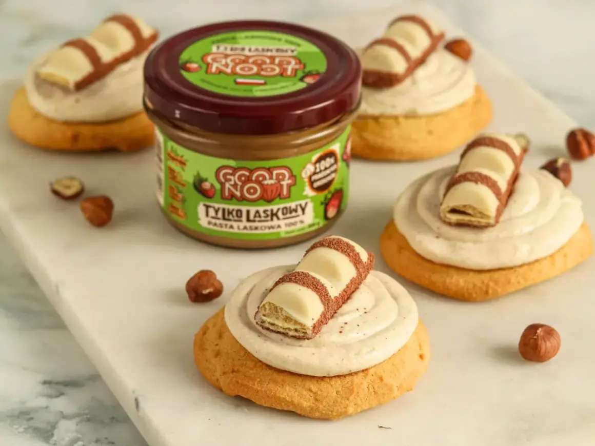 Pyszne ciasteczka inspirowane przepisem na crumbl cookies, z kremem i kawałkami Kinder Bueno. Słoik pasty z orzechów laskowych Good Now zachęca do eksperymentów.