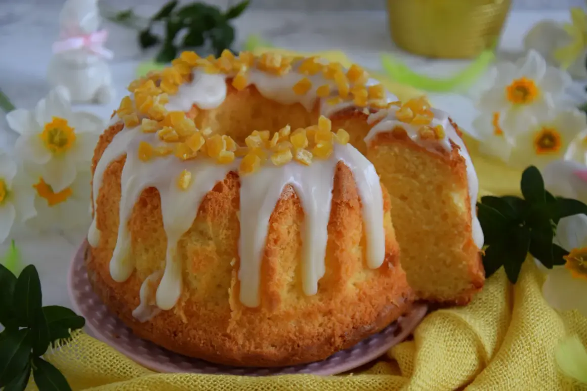 Puszysta babka majonezowa z lukrem i kandyzowaną skórką pomarańczową, ozdobiona wiosennymi kwiatami.