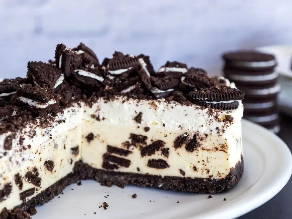 Pyszny sernik oreo z kawałkami ciastek i kremową masą, posypany pokruszonymi oreo.