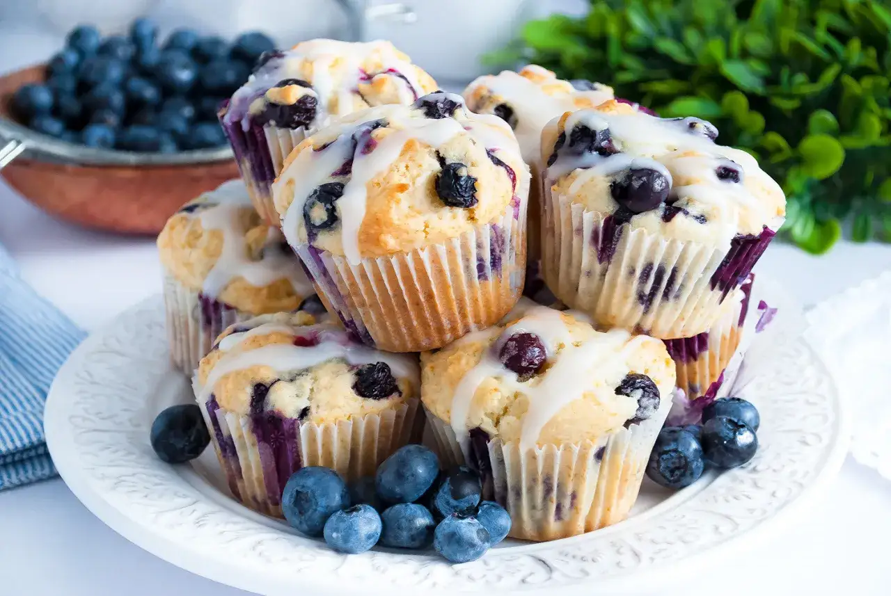 Stos pysznych muffinek z bor&oacute;wkami, polanych lukrem, ozdobionych świeżymi bor&oacute;wkami.