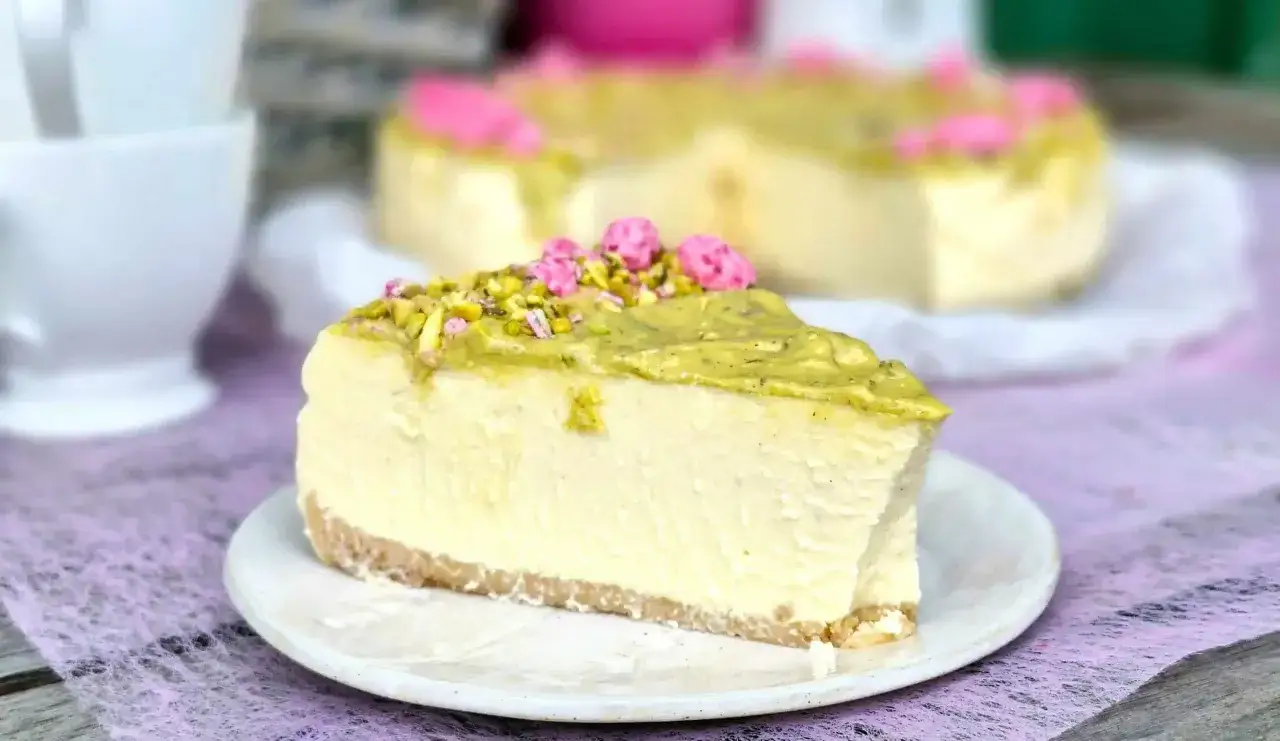Pyszny sernik w kąpieli wodnej, udekorowany pistacjami i r&oacute;żowymi kwiatkami. Idealny deser na każdą okazję.