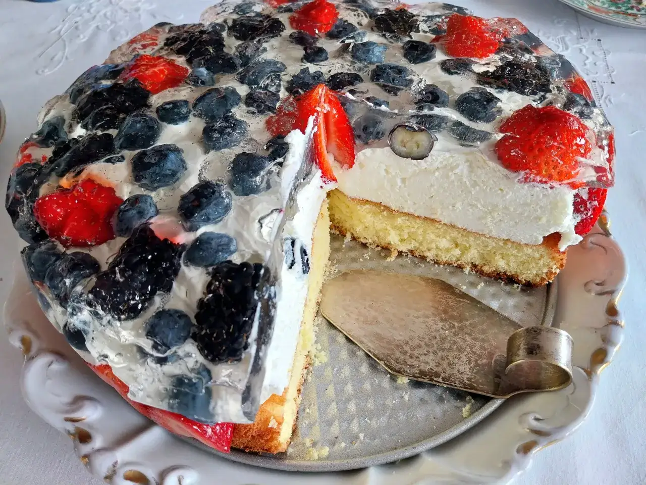 Biszkopt z puszystym serkiem mascarpone, przykryty galaretką z owocami leśnymi i truskawkami. Wygląda pysznie!
