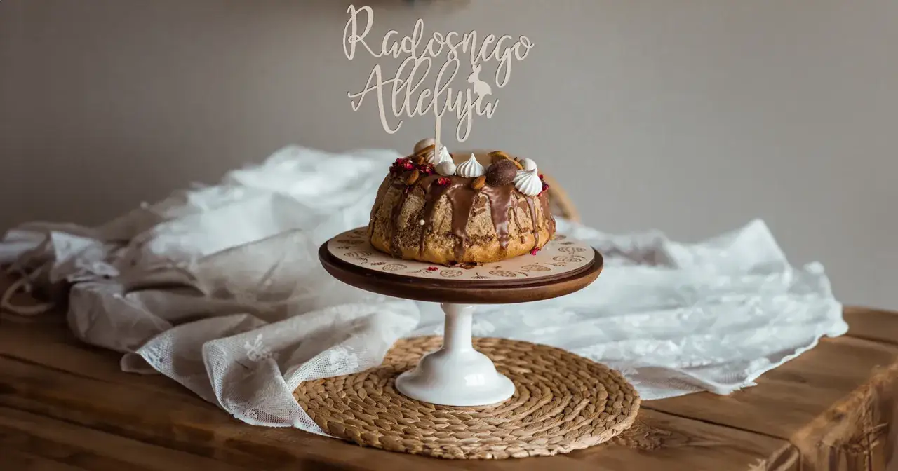 Eleganckie ciasta wielkanocne na drewnianej podstawce, ozdobione czekoladą i bezą. Napis 