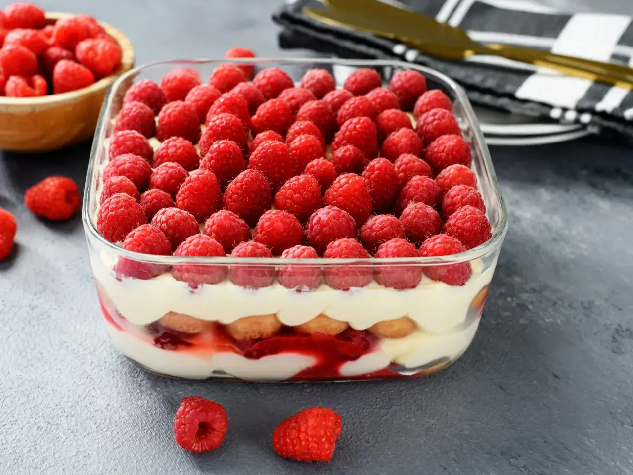 Pyszne tiramisu malinowe w szklanej formie, udekorowane świeżymi malinami.