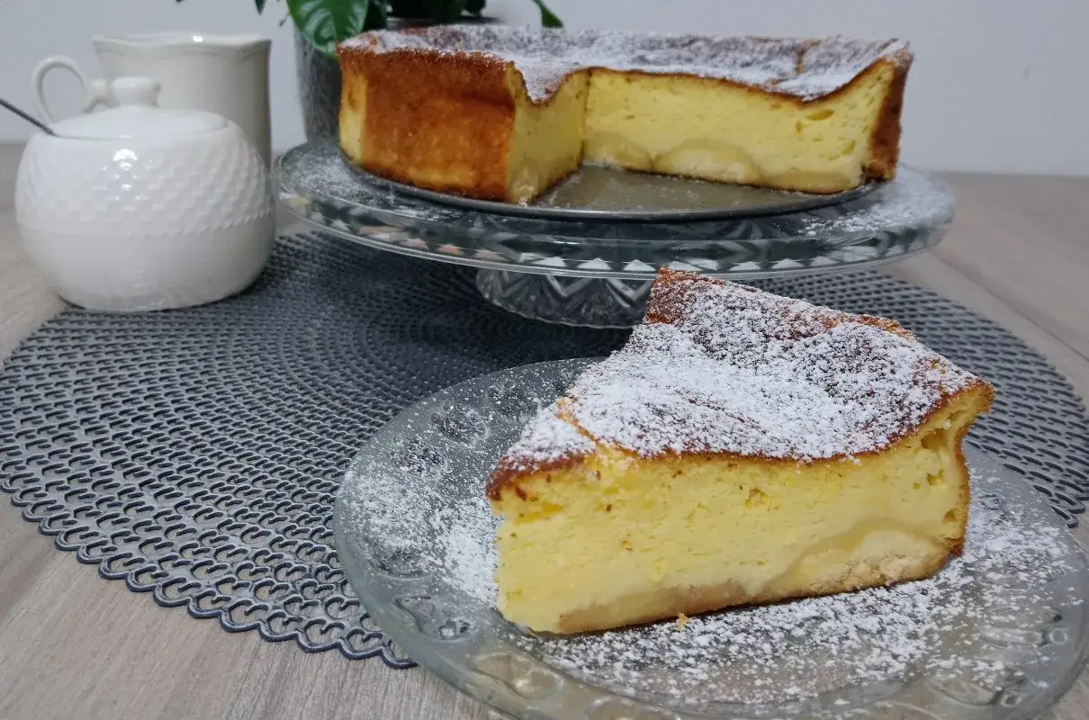 Pyszny sernik bez sera, z jabłkami i cukrem pudrem, wygląda apetycznie na talerzyku.
