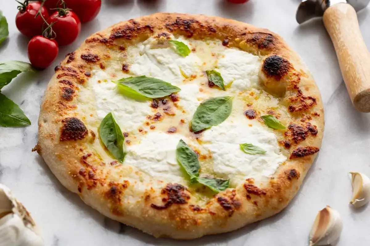 Pyszna pizza bianca z kremowym serem, świeżą bazylią i lekko przypieczonym ciastem. Idealna na szybki obiad.