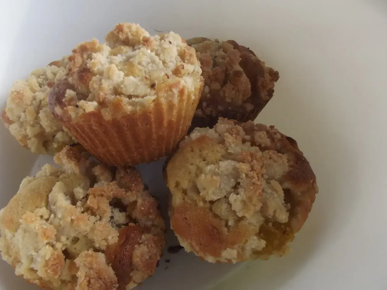 Cztery pyszne muffinki ze śliwkami, posypane kruszonką, kuszą swoim wyglądem.
