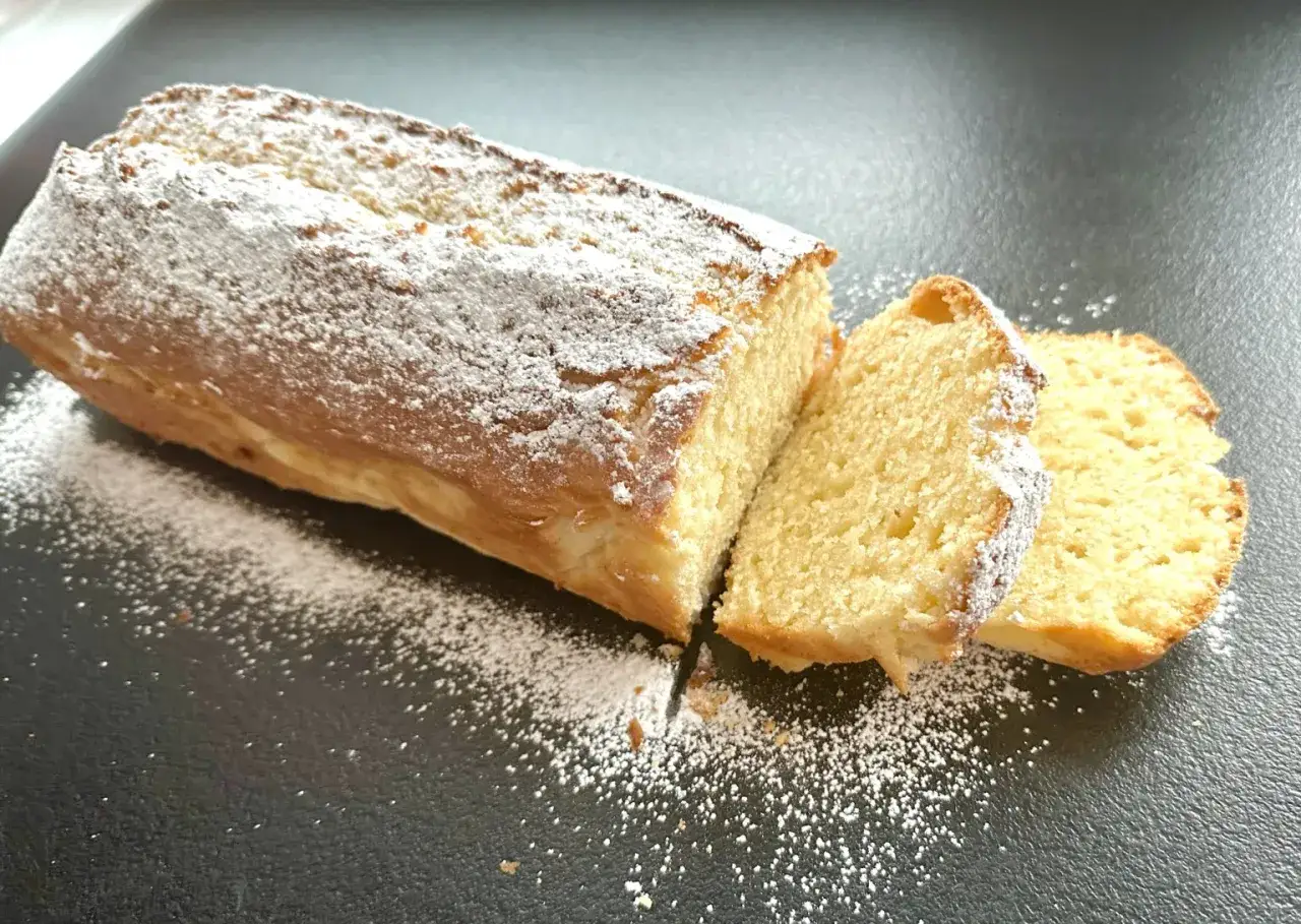 Wilgotna babka, opr&oacute;szona cukrem pudrem, kusi swoim apetycznym wyglądem. Dwa pokrojone kawałki ukazują jej puszyste wnętrze.