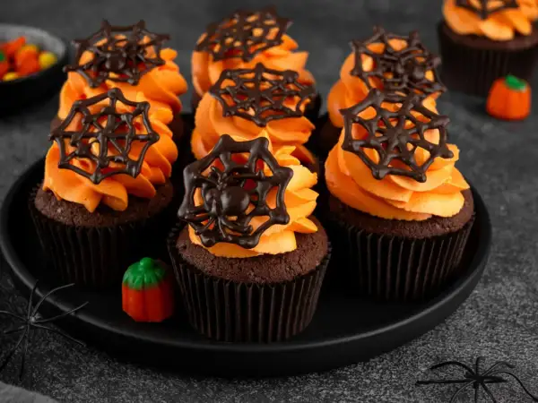 Przerażająco pyszne babeczki halloween z pomarańczowym kremem i czekoladowymi pajęczynkami. Idealne na straszne przyjęcie!