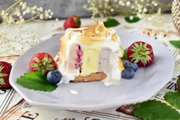 Pyszne baked alaska z lodami, owocami i bezą na talerzu.