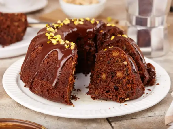 Pyszna babka czekoladowa z polewą i pistacjami, kawałek ciasta z orzechami i bakaliami.