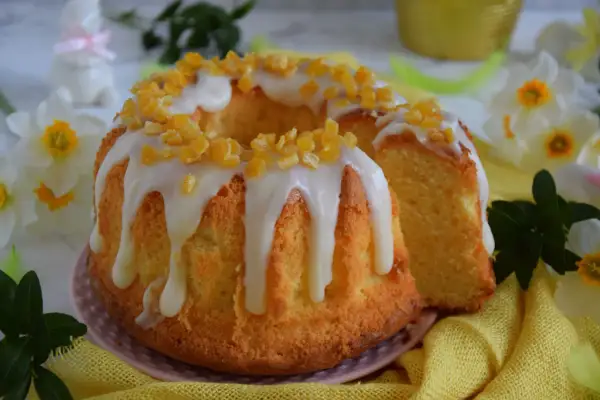 Puszysta babka majonezowa z lukrem i kandyzowaną skórką pomarańczową, ozdobiona wiosennymi kwiatami.